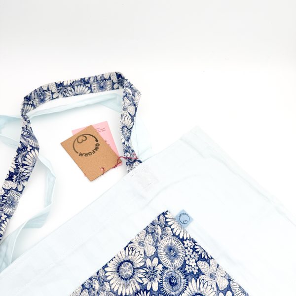 blå materiale med stribet motiv og en mørkeblå blomster mønstret lomme. Hanken er af samme materiale som lommen.