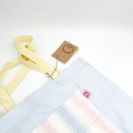 Dette net er af et lyseblåt materiale med en pastel stribet lomme med motiv. Hanken er gul.