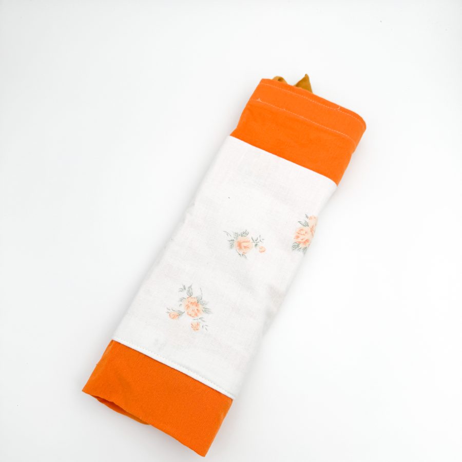 Dette net er af et orange materiale med hvid blomstret lomme og en mørkegul hank.