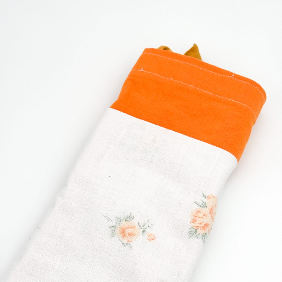 Dette net er af et orange materiale med hvid blomstret lomme og en mørkegul hank.