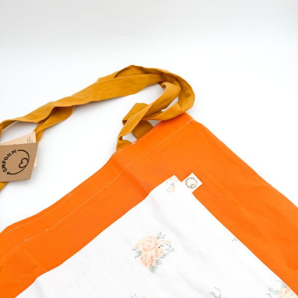 Dette net er af et orange materiale med hvid blomstret lomme og en mørkegul hank.